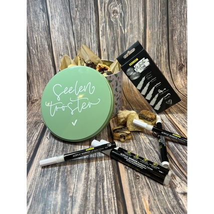 Acrylmarker in Weiß mit einem grünen Deko-Behälter und getrockneten Pflanzen im Hintergrund.