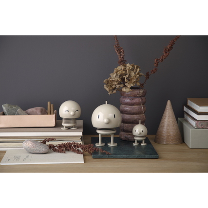 Dekorationsfigur in Form eines lächelnden Charakters aus hellem Material auf einem Tisch mit Deko.