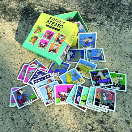 Gesellschaftsspiel "Findet Memo" mit Karten und Verpackung auf einem Untergrund aus Beton.