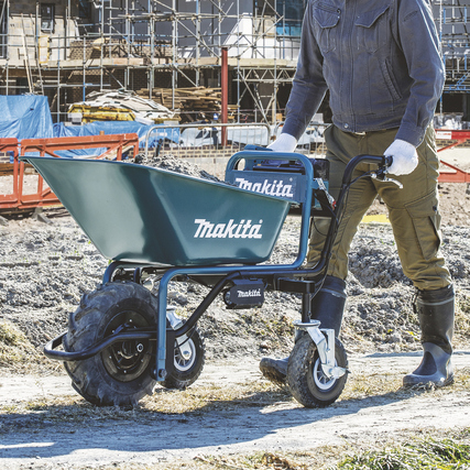 Akku-Schubkarre mit einem Mann, der sie auf einer Baustelle schiebt.