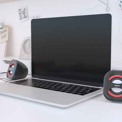Aktiver 2.0-Lautsprecher auf einem Tisch neben einem Laptop, mit USB-A-Stromversorgung.