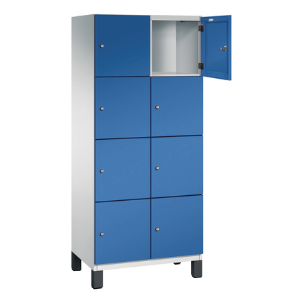 Lichtgrauer Schließfachschrank mit acht Fächern, eine Tür offen, auf Kunststofffüßen.