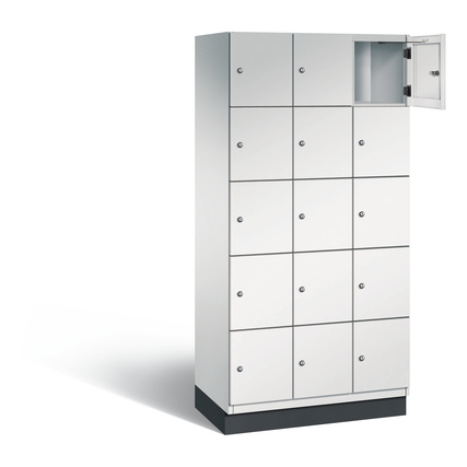 Schließfachschrank mit 15 Fächern, geöffnetes Fach, lichtgraue Oberfläche, auf Sockel.