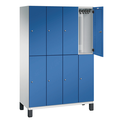 Doppelstöckiger lichtgrauer Kleiderspind mit 8 blauen Fächern und offenen Türen.