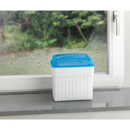 Luftentfeuchter auf Fensterbank mit feuchtem Hintergrund und unauffälligem Design.