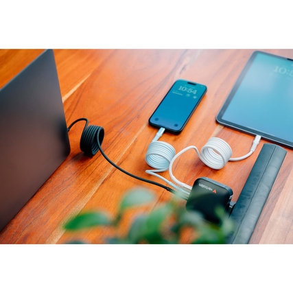 USB-C-Kabel mit angeschlossenen Geräten auf einem Tisch, Kabelaufbewahrung in spiralförmiger Form.