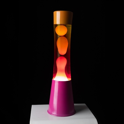 Pink-orange Lavalampe auf einem weißen Tisch mit blubbernden Flüssigkeitsblasen.