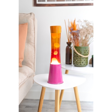 Lavalampe in pink und orange auf einem Tisch neben einem Sofa und dekorativen Elementen.