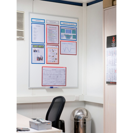 Weißes Whiteboard mit verschiedenen Informationen und Diagrammen an einer Bürowand montiert.