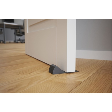 Türstopper aus Elastomer blockiert Tür in offener Position auf einem Holzfußboden.