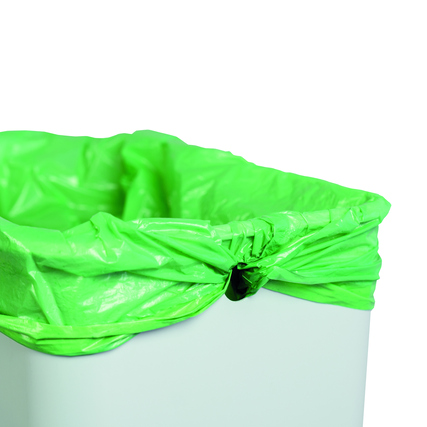 Grüner Müllbeutel in einem weißen Abfalleimer mit leichtem Überhang am Rand.