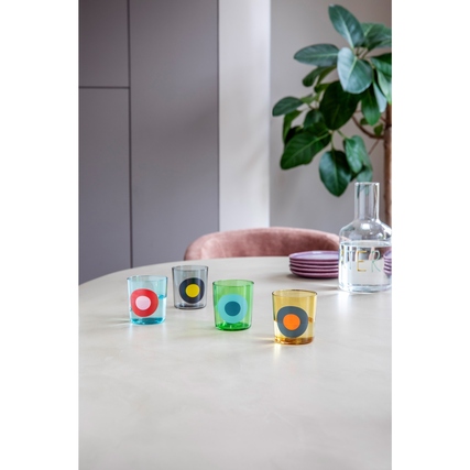 Vier bunte Trinkgläser mit Punkten auf einem Tisch in einem modernen Umfeld.