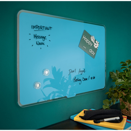 Blaues Glasboard an einer Wand mit Notizen, Magneten und dekorativen Elementen.
