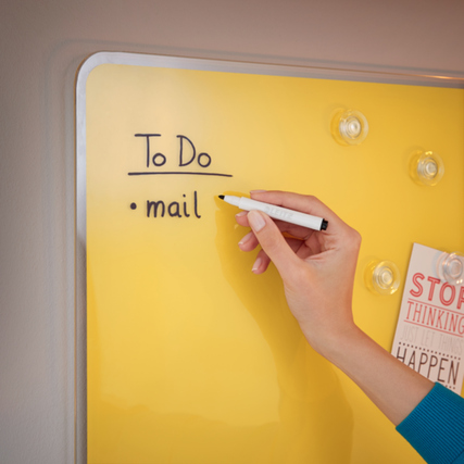 Gelbes Glasboard mit handgeschriebenem 'To Do' und einer Person, die mit einem Stift schreibt.