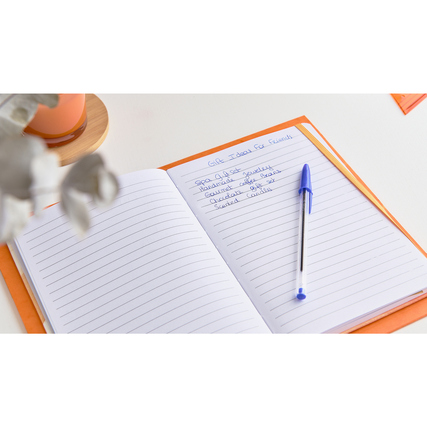 Kugelschreiber auf offenem Notizbuch mit handschriftlicher Liste, Tasse im Hintergrund.