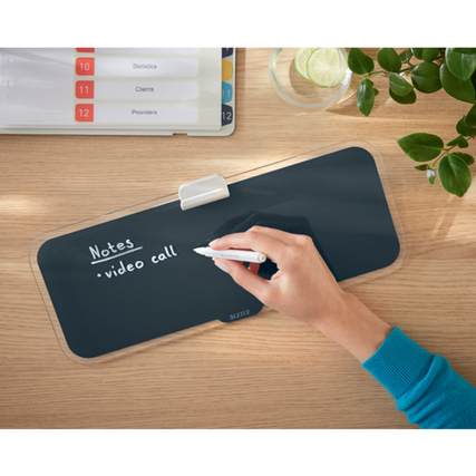 Graues Memoboard mit handschriftlichen Notizen und einer Hand, die mit einem Stift schreibt.