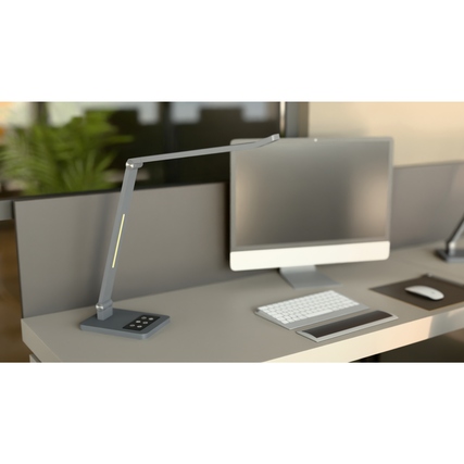 Hansa Tischleuchte Tide in metallgrau, auf einem Schreibtisch neben einem Computer und Tastatur.