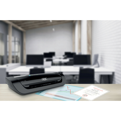 Laminiergerät auf einem Tisch in einem modernen Büro mit Dokumenten daneben.