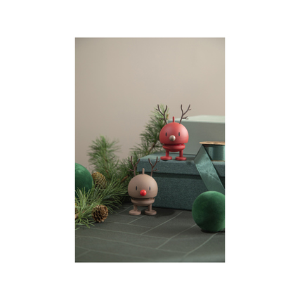 Zwei dekorative Elchfiguren aus Kunststoff auf einem Tisch mit Geschenkboxen und Tannenzweigen.