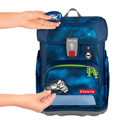 Zwei Hände bringen einen Anhänger an einen Schulranzen mit einem starry Design an.