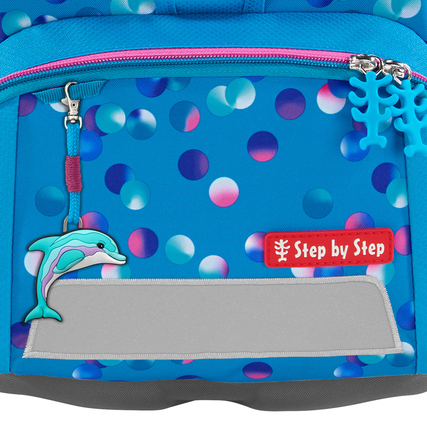 Delfin-Anhänger an einem blauen Schulranzen mit bunten Punkten als Beispiel für Individualisierung.