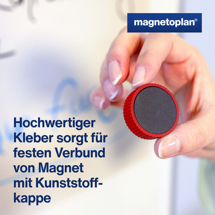 Roter Magnet mit Kunststoffkappe in Hand, auf einer Tafel hinterlegt.