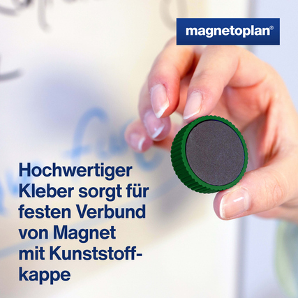 Grüner Magnet mit Kunststoffkappe wird von einer Hand an einer Tafel platziert.