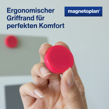 Pinkfarbener Ergo-Magnet in Hand mit ergonomischem Griffrand vor einer Tafeloberfläche.