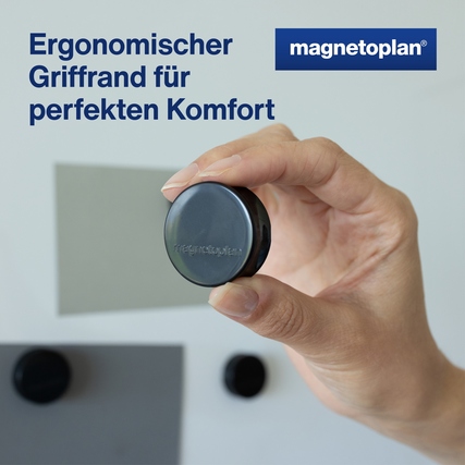 Schwarzer Ergo-Magnet mit Hand im Vordergrund, der an einer glatten Oberfläche haftet.