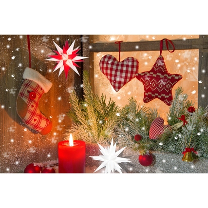 Weißer Herrnhuter Stern (13 cm) vor festlicher Weihnachtsdekoration mit Kerze und Stoffherzen.