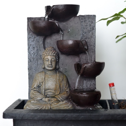 Buddha-Statue mit Wasserfall und Schalen in einem Pflanzgefäß für einen Bonsai-Baum.