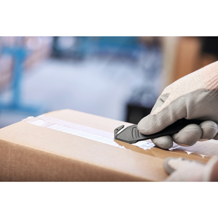 Ein Handwerker schneidet mit einem Sicherheitsmesser vorsichtig das Klebeband einer Kartonage ab.