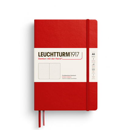 Rotes Hardcover-Notizbuch mit punktkarierten Seiten und einem schlichten, weißen Etikett.