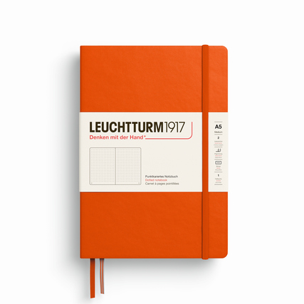 Punktkariertes Hardcover-Notizbuch in Kürbis-Orange mit weißem Etikett und Gummiband.