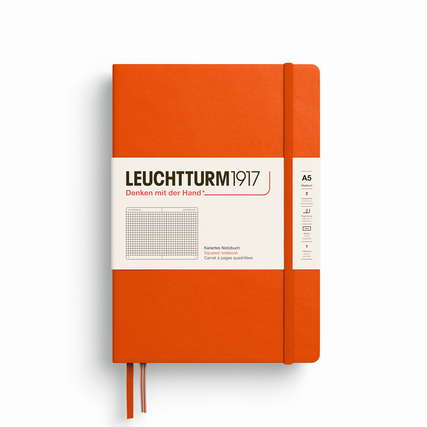 Oranges Hardcover-Notizbuch mit kariertem Innenteil und sichtbarem Stiftband.