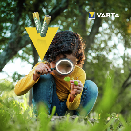 Umweltfreundliche Varta Recycled AAA/Micro Akkus liegen neben einem Kind, das in der Natur sitzt.