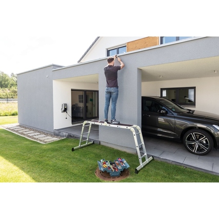 Multifunktionsleiter in Nutzung als Stehleiter vor einem modernen Haus mit Rasenfläche.
