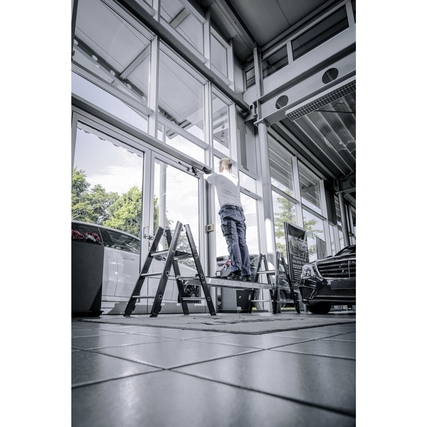 Klapptritt in Verwendung, Person steht auf der Plattform und erreicht ein Fenster in hoher Höhe.