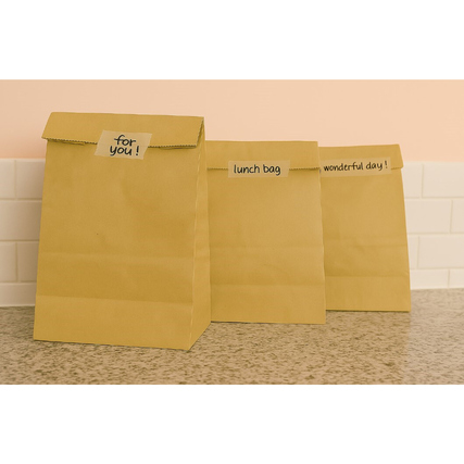 Transparentes tesafilm® PAPER Klebeband auf braunen Papierbeuteln mit Beschriftungen.