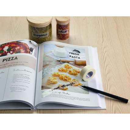 Transparentes tesafilm® PAPER Klebeband auf einer offenem Rezeptbuchseite, neben Gewürzgläsern.