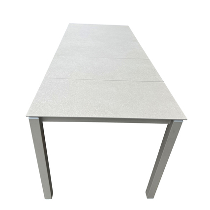 Ausziehtisch in Zementoptik mit stabilem Gestell, von vorne mit heruntergeklappten Einlegeplatten.