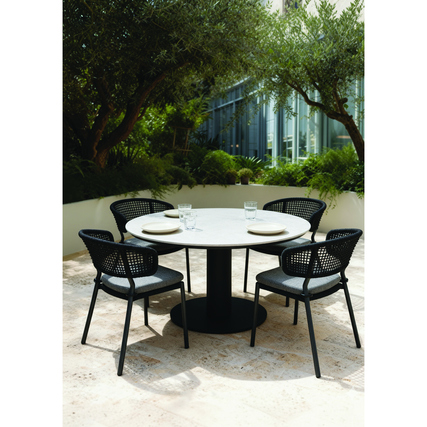 Gartentisch mit runder Tischplatte und vier Stühlen in einer begrünten Umgebung.