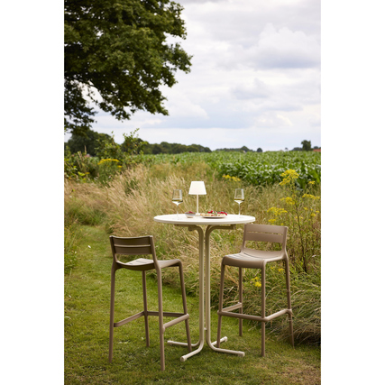 Barhocker in sandfarbener Ausführung stehen an einem Tisch im Freien, umgeben von Natur.