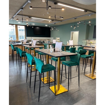 Grüne Barhocker mit industriellem Design in einer modernen Gastronomieumgebung.