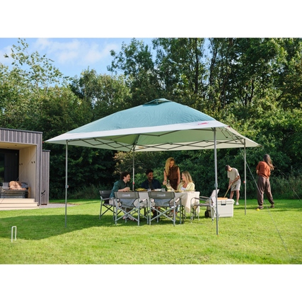 Pavillon mit geöffneter Dachkonstruktion und Menschen, die an einem Tisch im Freien sitzen.