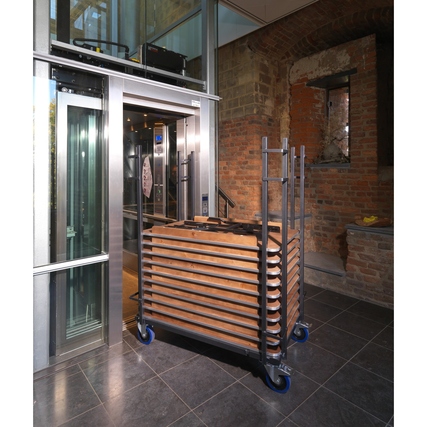 Transportwagen für rechteckige Banketttische, im Einsatz vor einem Aufzug.
