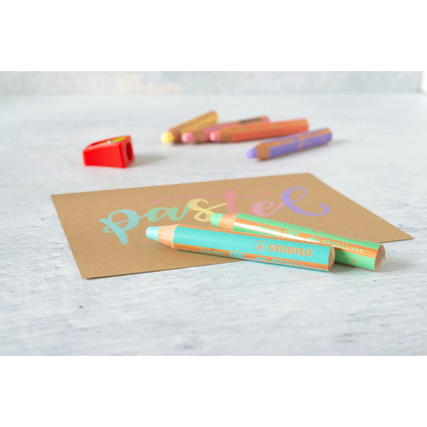 Buntstifte in Pastellfarben und ein Spitzer auf braunem Papier mit dem Wort ‚pastel‘.