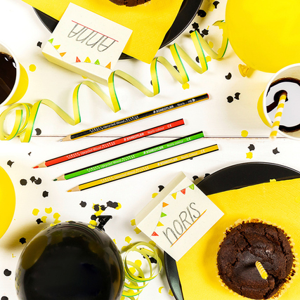 Buntstifte in verschiedenen Farben auf einem Tisch mit Partydekoration und einem Muffin.