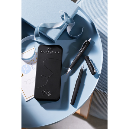 Füllfederhalter in Schwarz auf einem Tisch neben Schreibutensilien und einer Box.