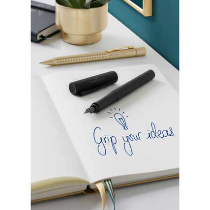Füllfederhalter in Schwarz liegt offen auf einem Notizbuch mit dem Text "Grip your ideas."